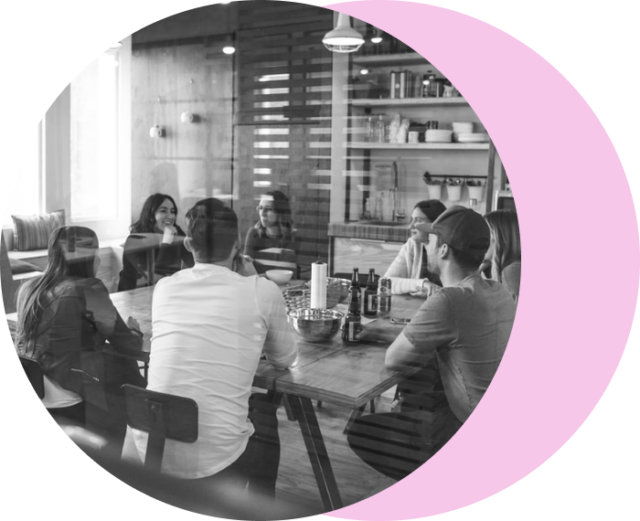 black and white photo of a team of people sitting around a table.