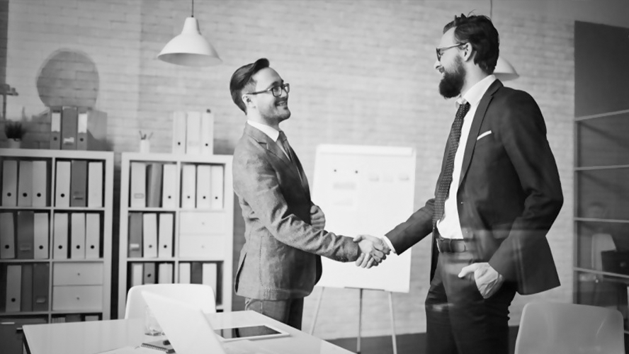 Two businessmen shaking hands in an office setting.