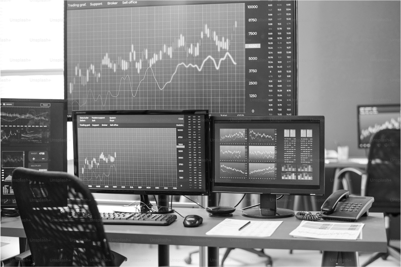 Financial trading workstation with multiple screens displaying graphs and data analysis.
