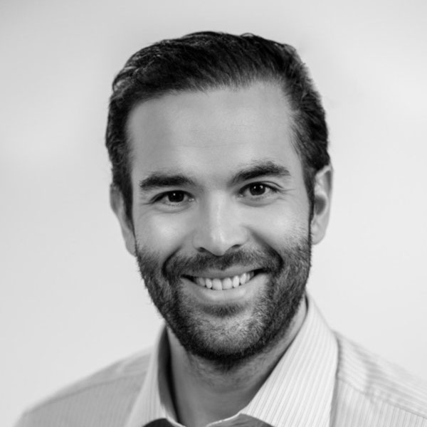 Black and white portrait of a smiling man with a beard, wearing a collared shirt at Zuora Subscribed Live.