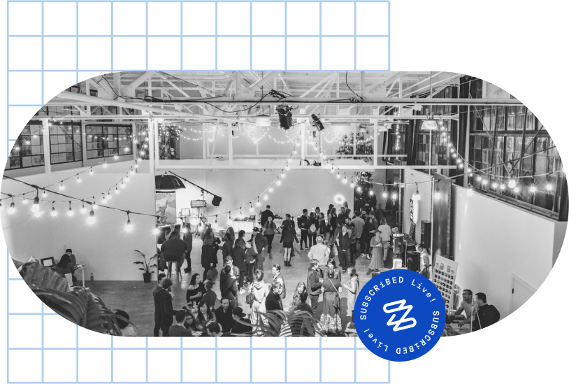 An indoor event with guests mingling under string lights in a spacious venue at the "Zuora Subscribed Live".