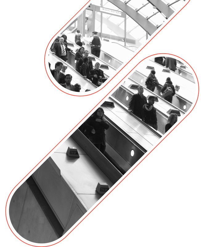 Black and white image of people using escalators in a modern building with windows above and sleek handrails.