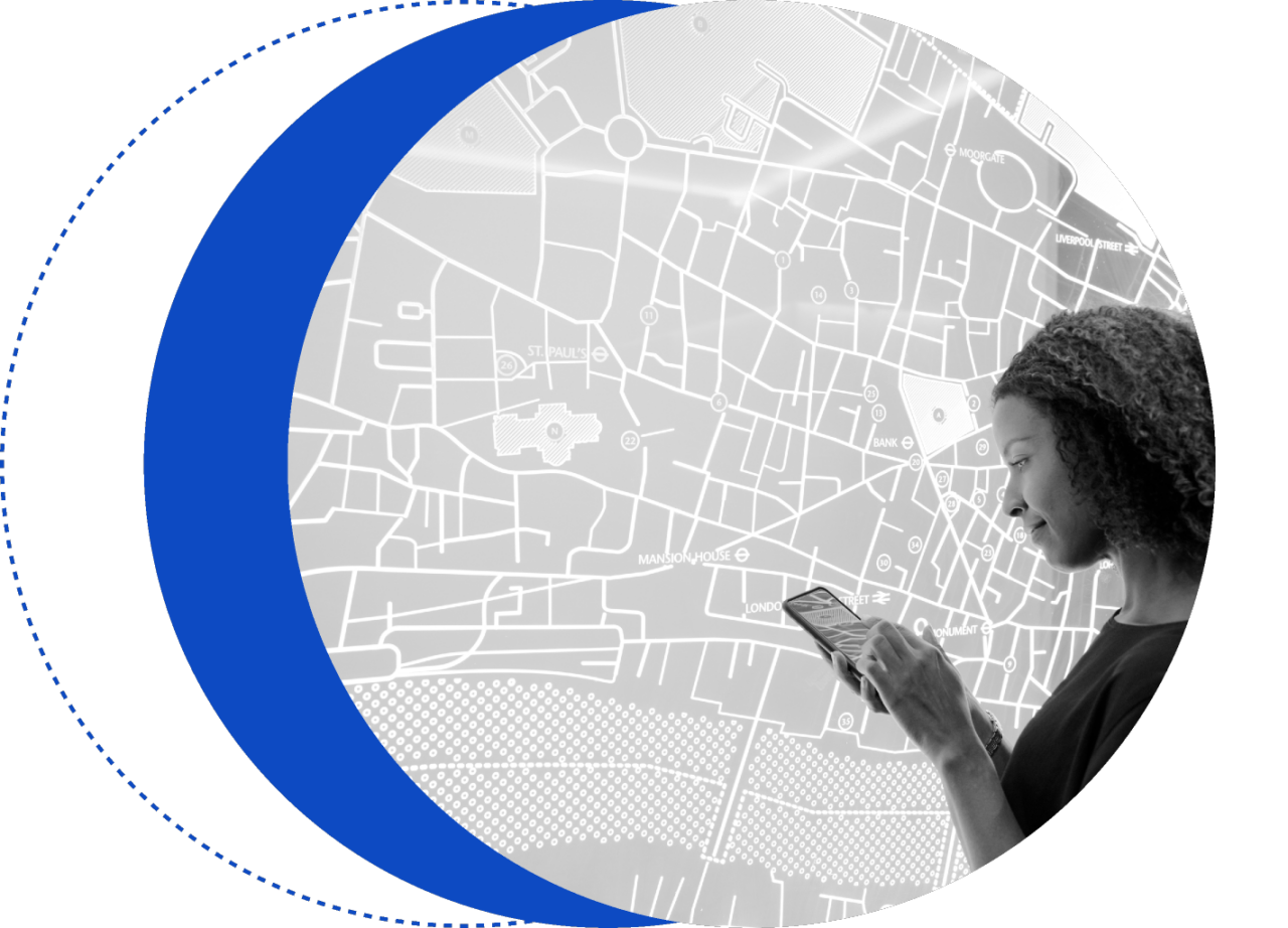 A person stands in front of a large map, looking down and using a smartphone. Several overlapping blue circles are partially shown on the left side of the image.