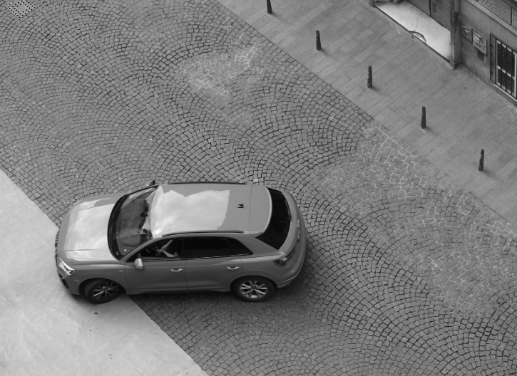 Aerial view of a car making a U-turn on a cobblestone street.