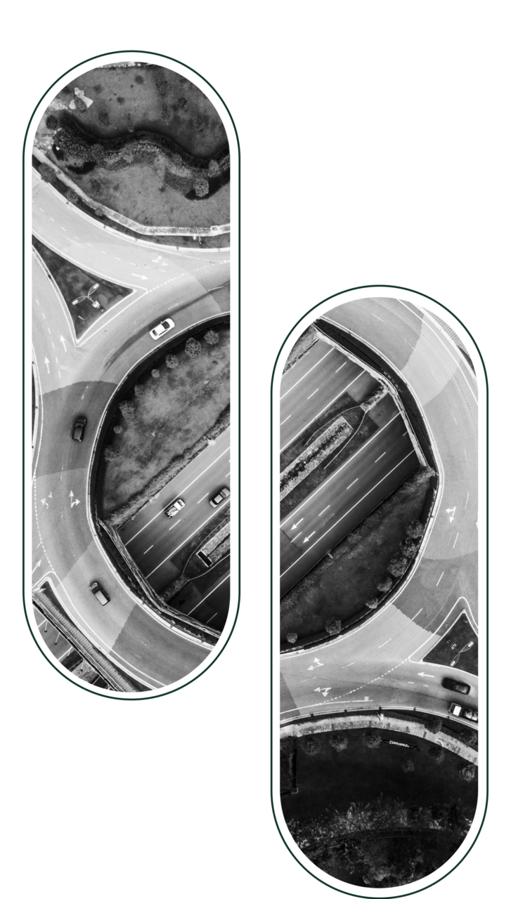 Black and white aerial view of two adjacent circular highway interchanges with vehicles, surrounded by grassy areas.