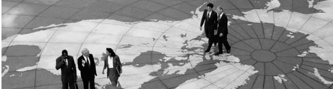 People walking on a large world map design on the ground, with some dressed in business attire.