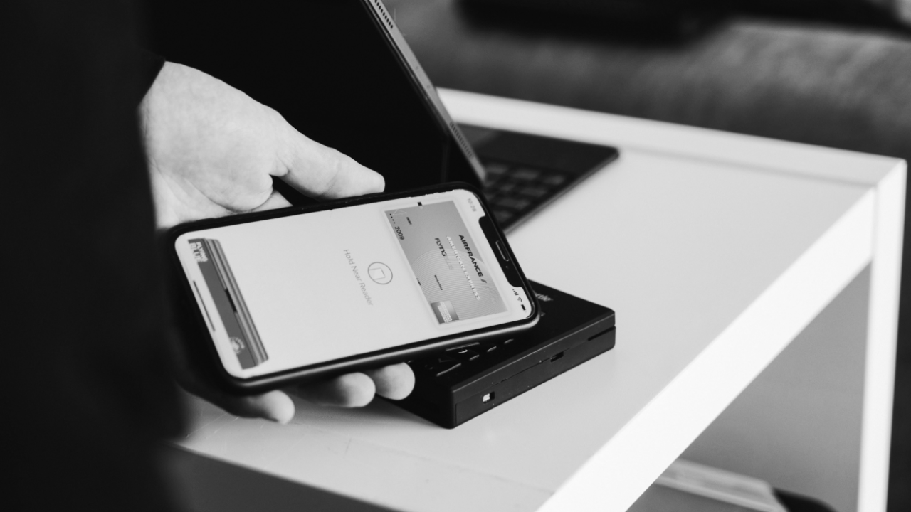 Person holding a smartphone over a payment terminal, preparing to make a contactless payment.