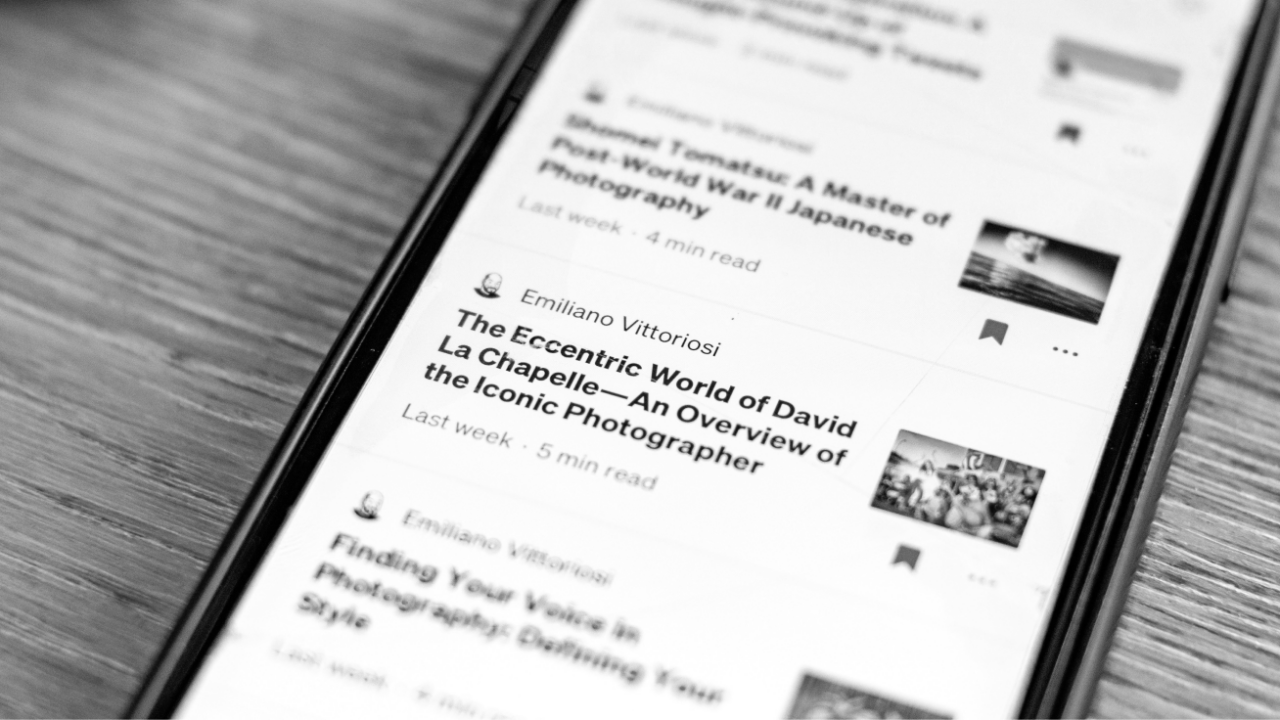 A smartphone displaying an article list, with one titled "The Eccentric World of David La Chapelle—An Overview of the Iconic Photographer," showing a small thumbnail image.