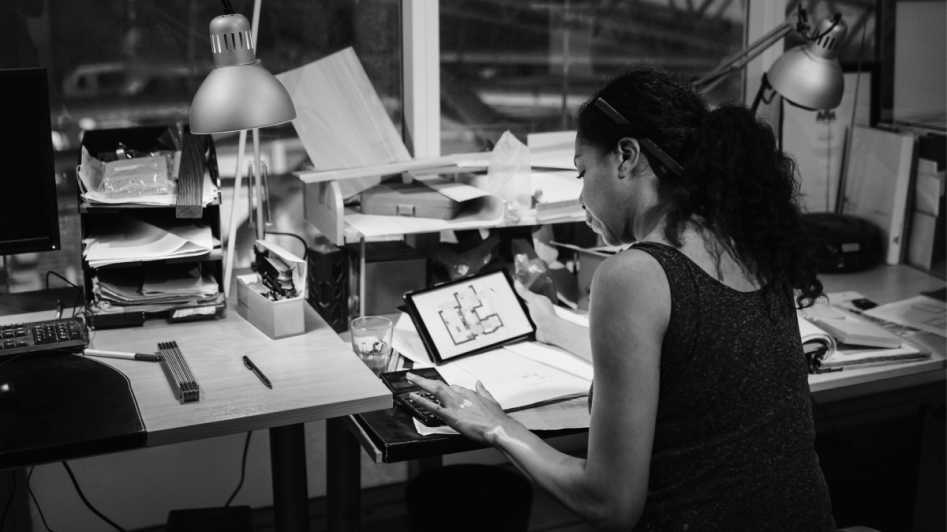 A finance professional sits at a desk with looking at charts and a calculator