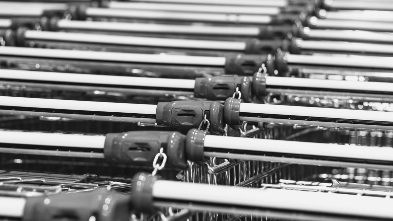 Rows of shopping cart handles lined up closely together.